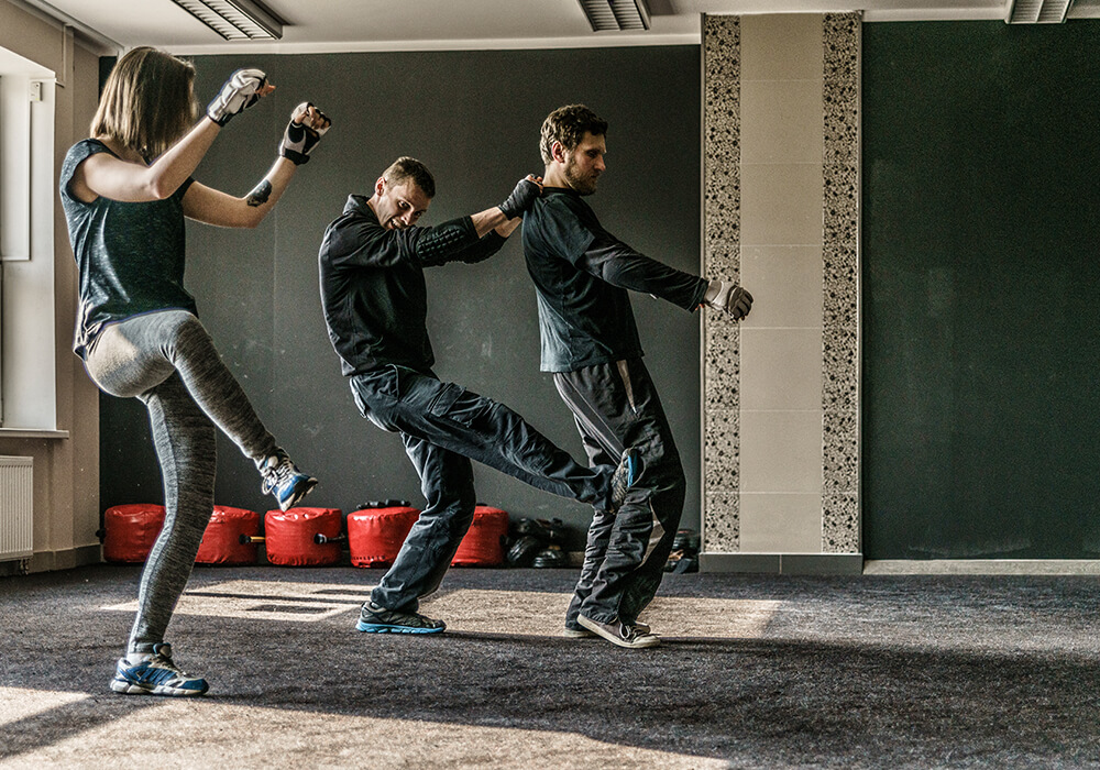 Adults practicing kicks together during Krav Maga training